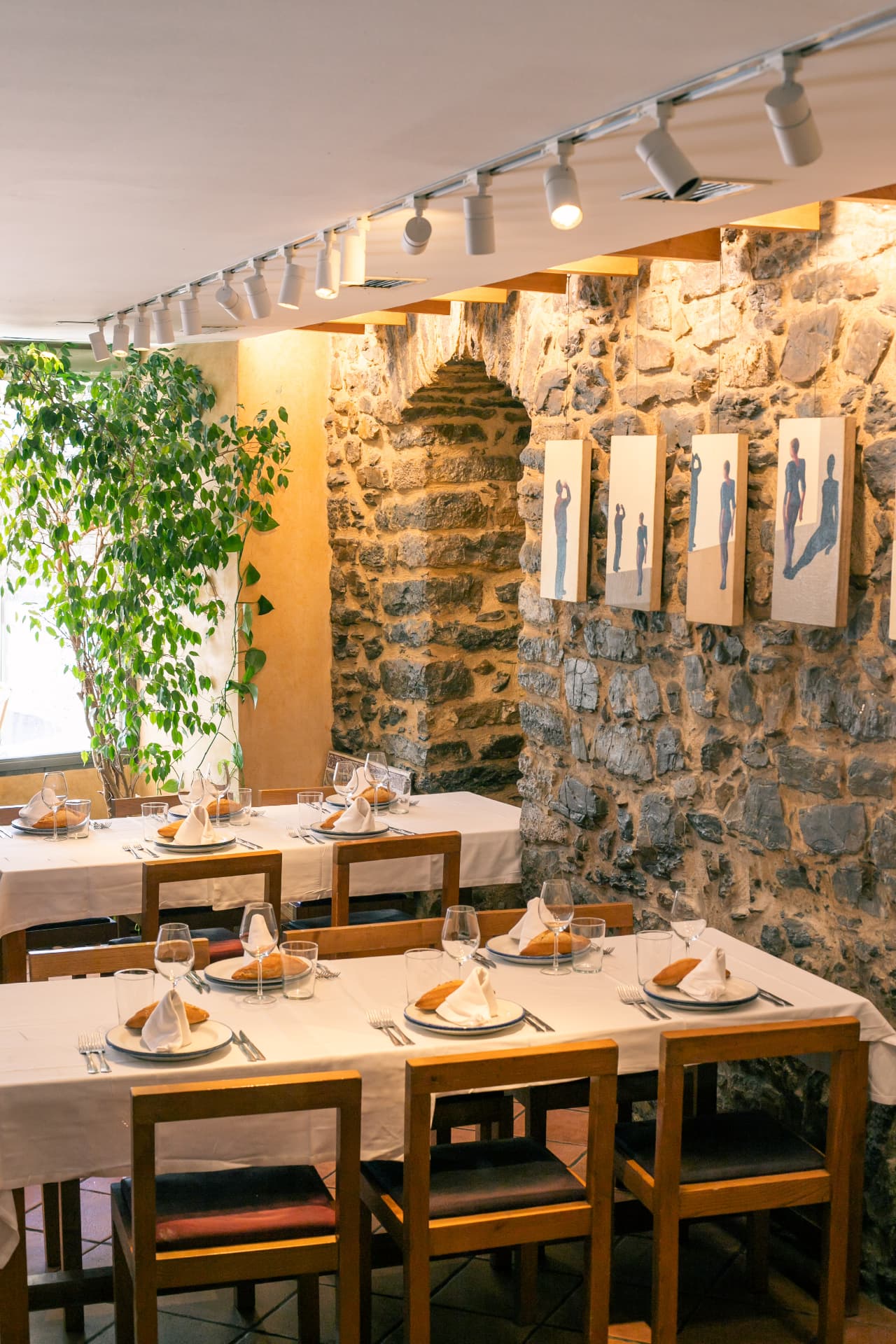 Comedor con obras de arte sobre muro de piedra
